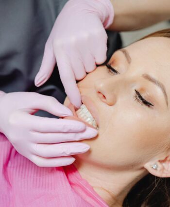 A dentist wearing gloves examines a patient's teeth in a close-up view during a dental check-up.
