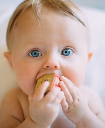 selective focus photography of baby holding wooden cube